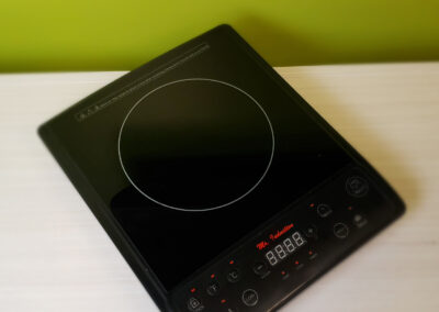 A black induction cooktop on a wooden shelf