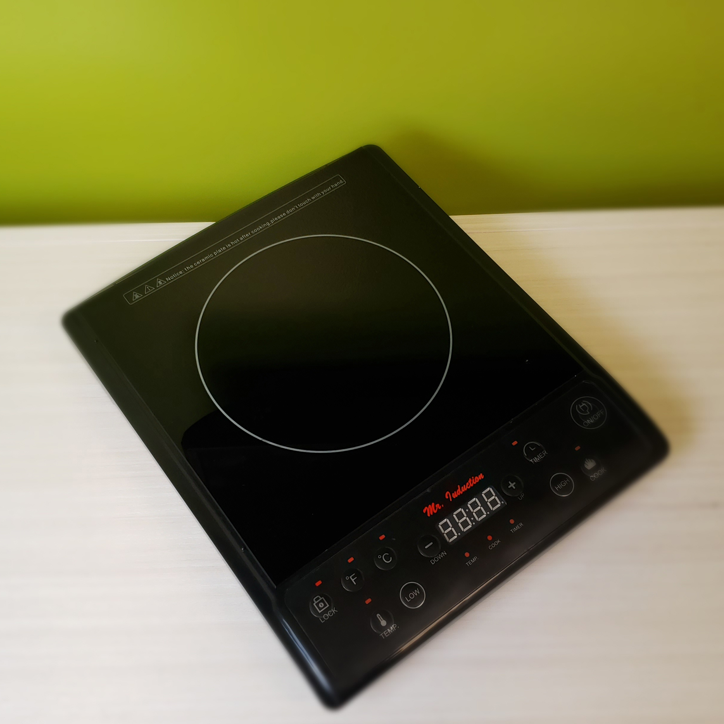 A black induction cooktop on a wooden shelf