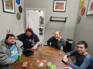A smiling group of four young men play a card game
