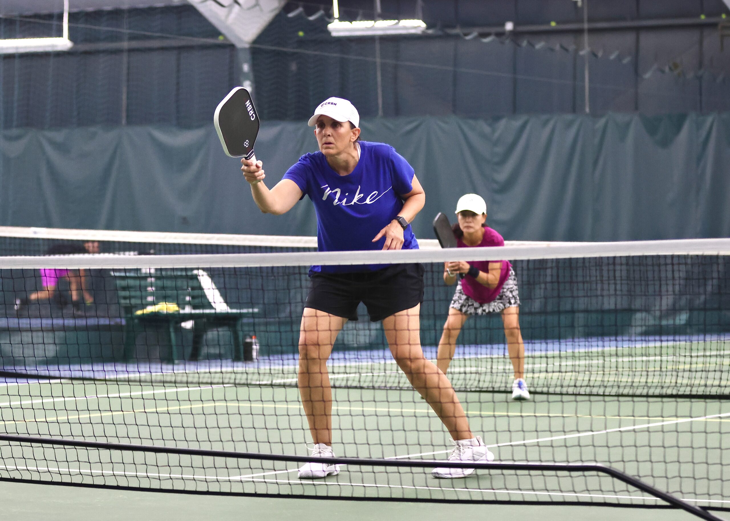 A woman in a blue shirt prepares to hit the ball